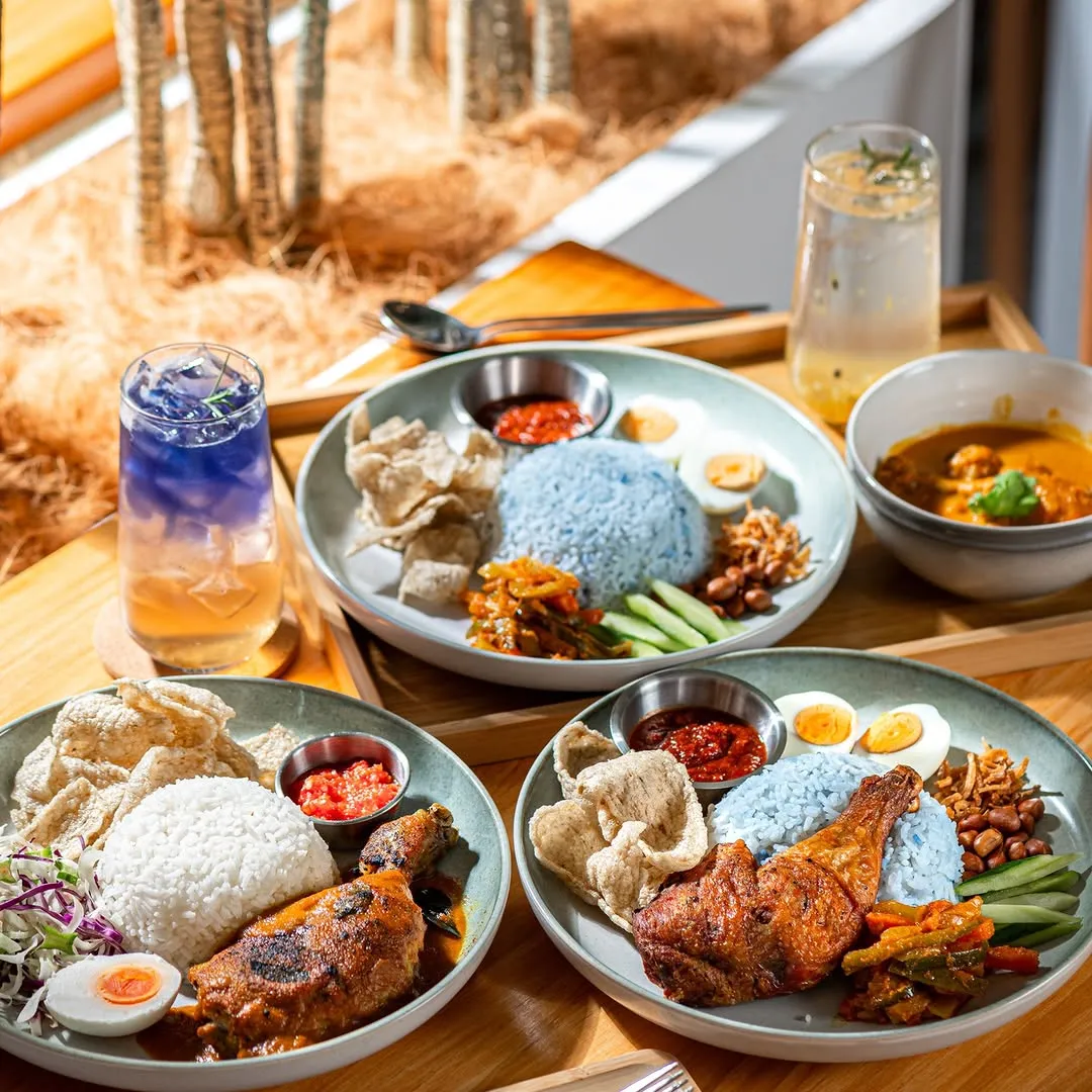 Colorful plates with chicken, rice, and condiments on a wooden table.