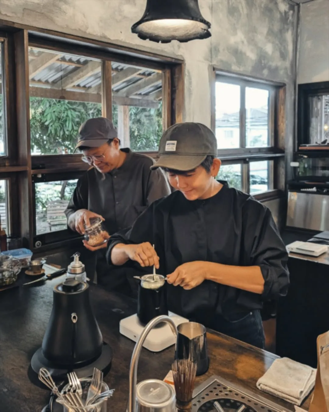 Baristas preparing drinks in a warm, rustic cafe environment.