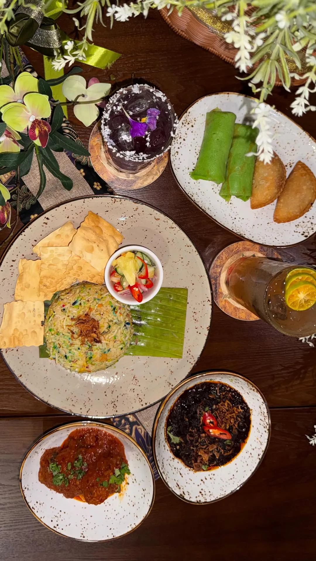 A top-down view of a vibrant meal with rice, curry, and snacks on a table.