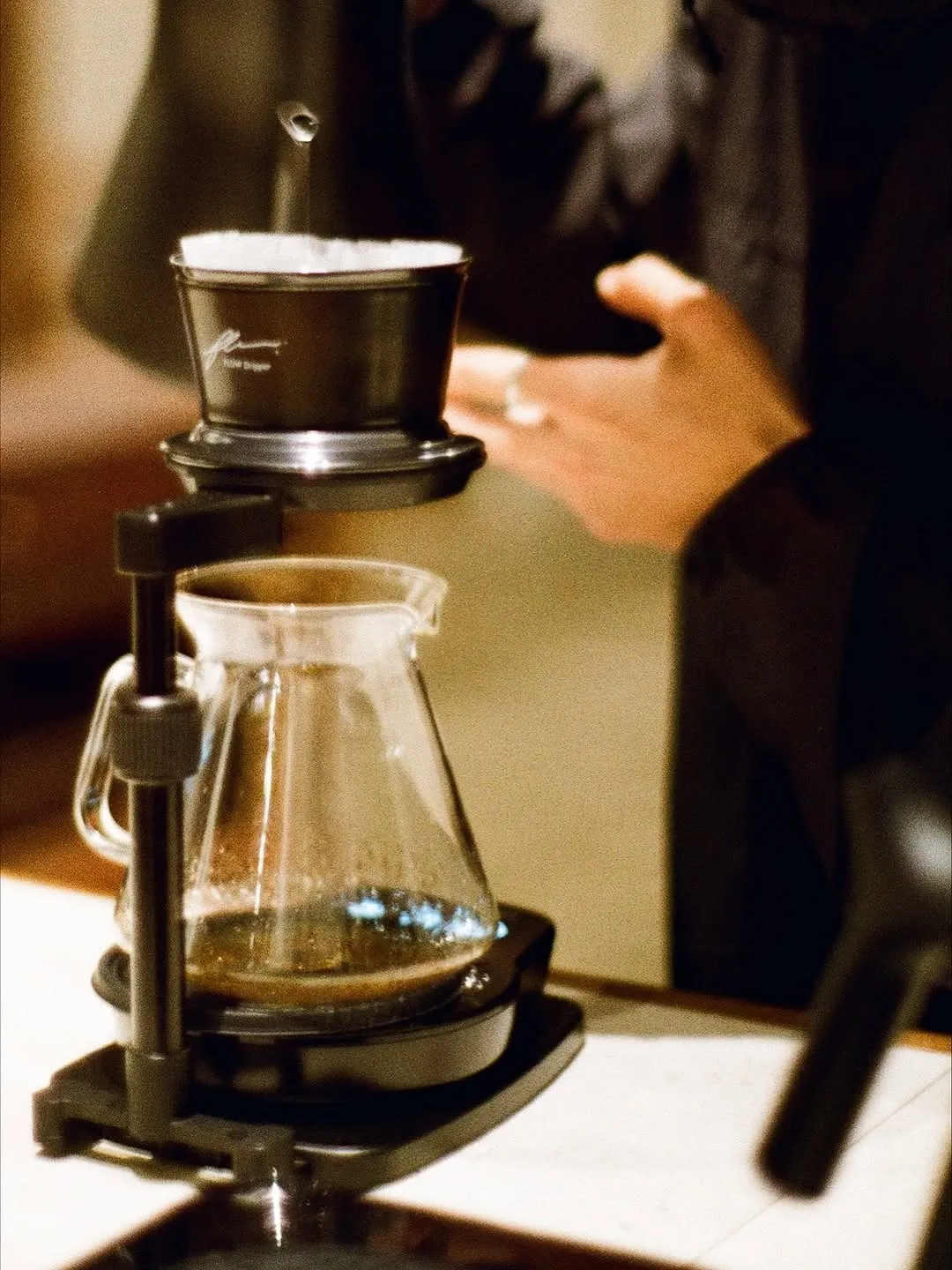 Brewing coffee meticulously with a pour-over setup and glass carafe.
