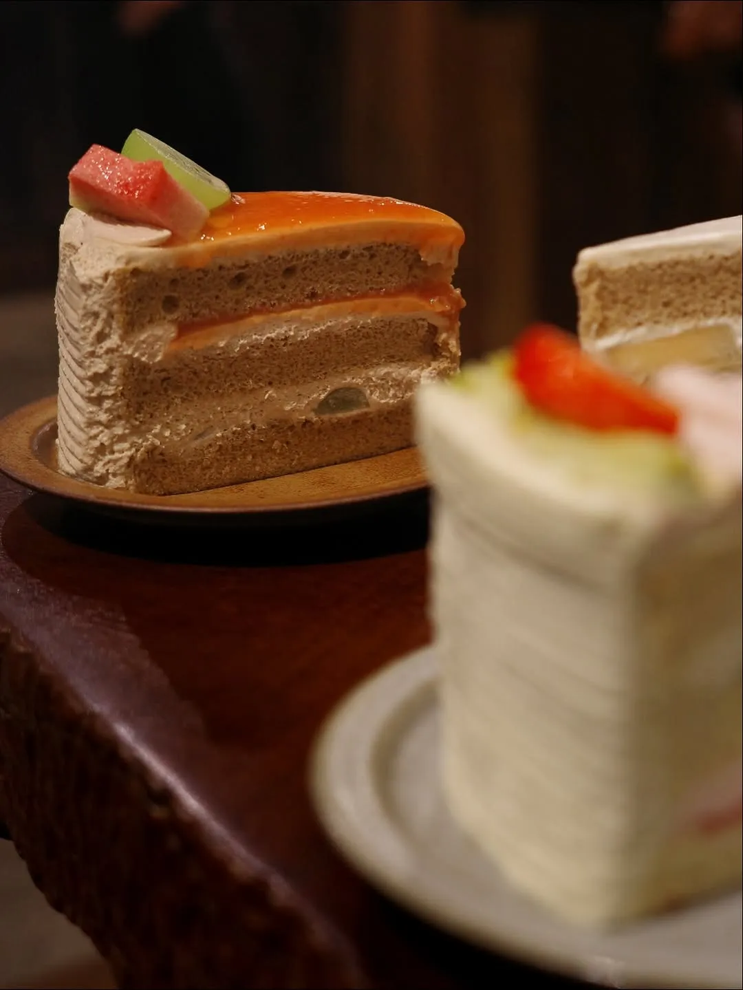 Layers of pistachio strawberry and jasmine melon cakes on wooden plates.
