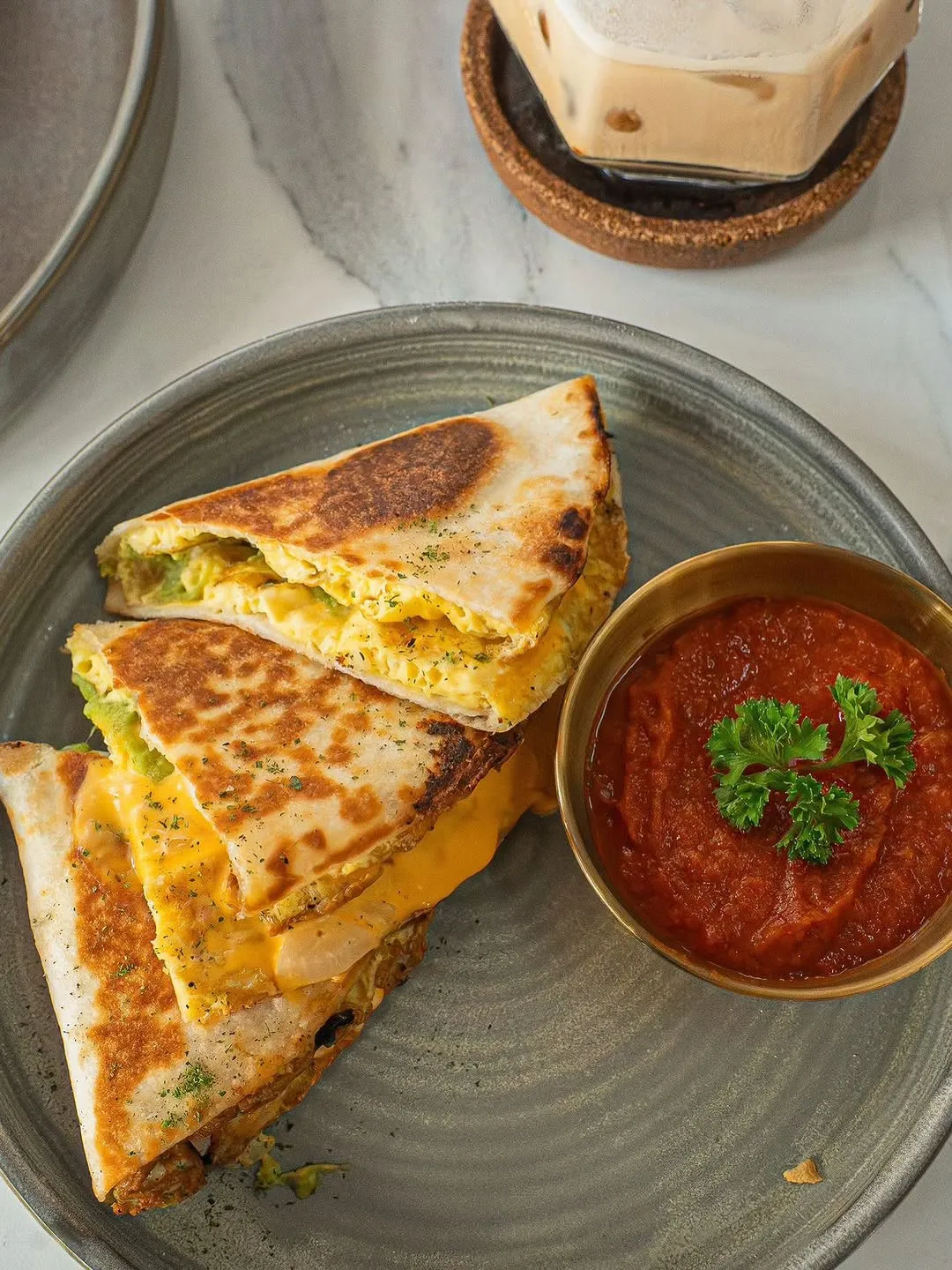 A quesadilla with melted cheese, served with a red sauce.