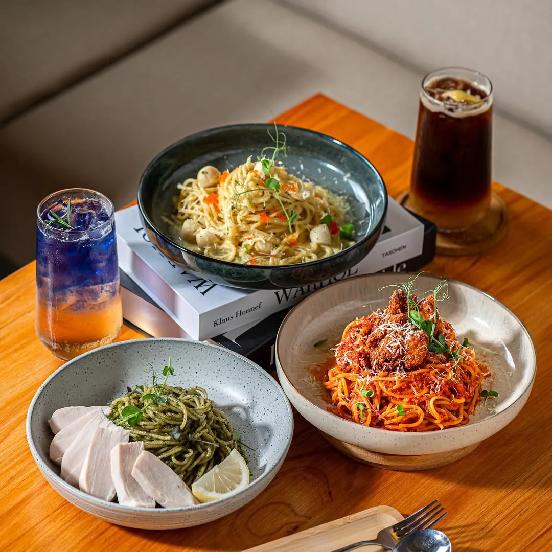 Three pasta dishes paired with refreshing drinks on a wooden table.