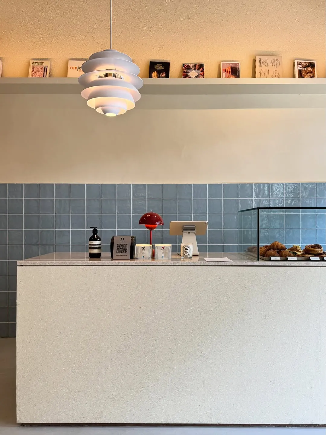 Minimalist cafe counter featuring baked goods and striking pendant lights.