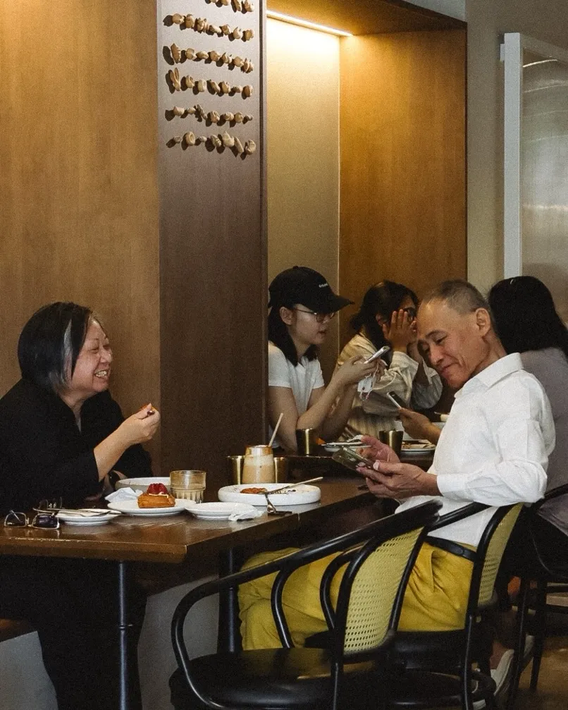 Two diners enjoying pastries and drinks in a cozy cafe setting, laughing together.