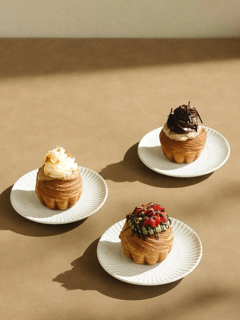 Three delicious pastries on white plates, beautifully styled against a neutral background.