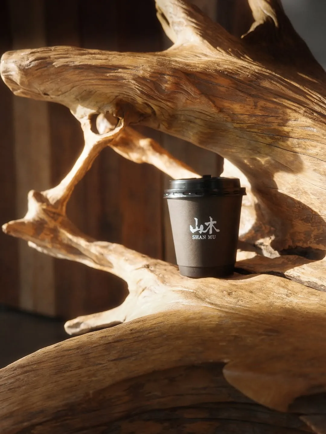 Warm coffee cup resting on rustic wooden sculpture accentuating coziness.
