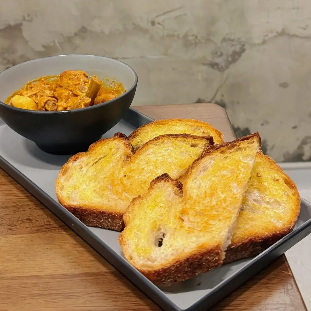 Toasted sourdough slices with curry chicken served in a bowl.