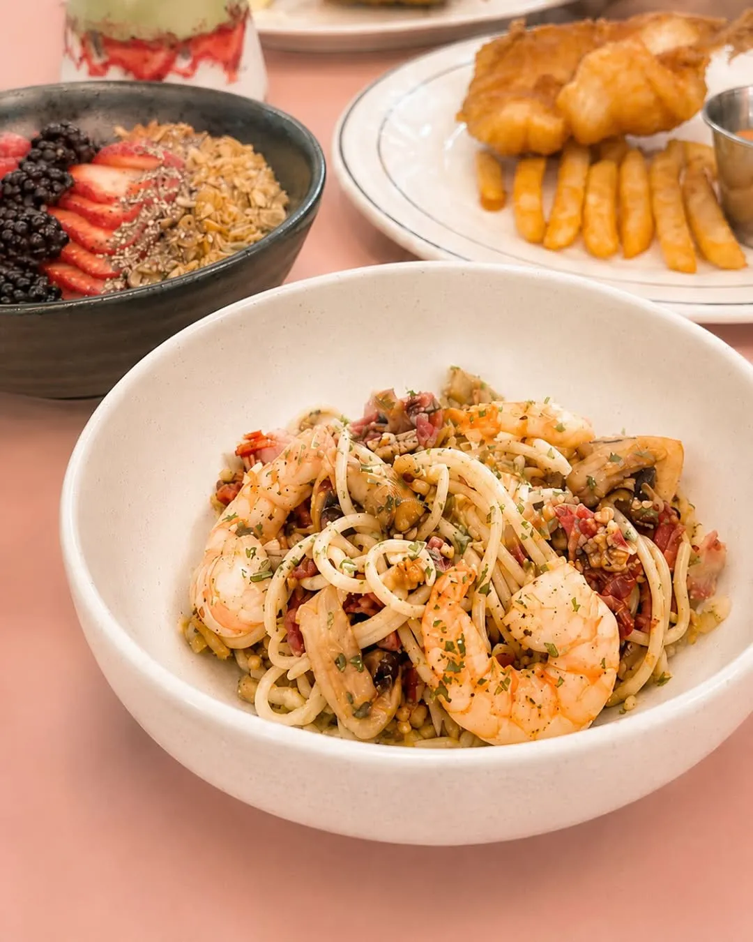 Seafood Aglio Olio topped with prawns and smoked duck, garnished with herbs.