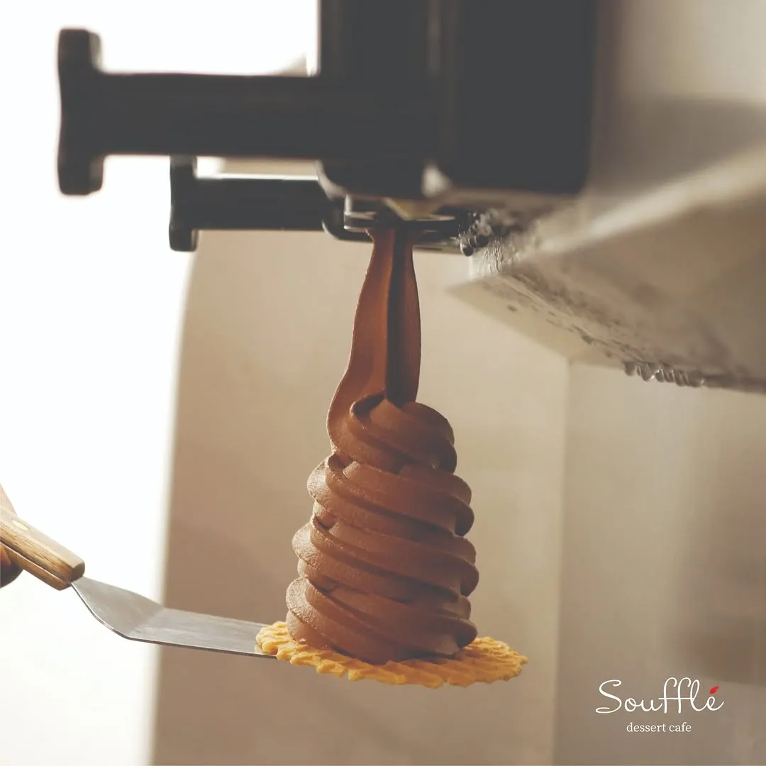 Chocolate swirl soft serve being plated on a waffle cone at the cafe.