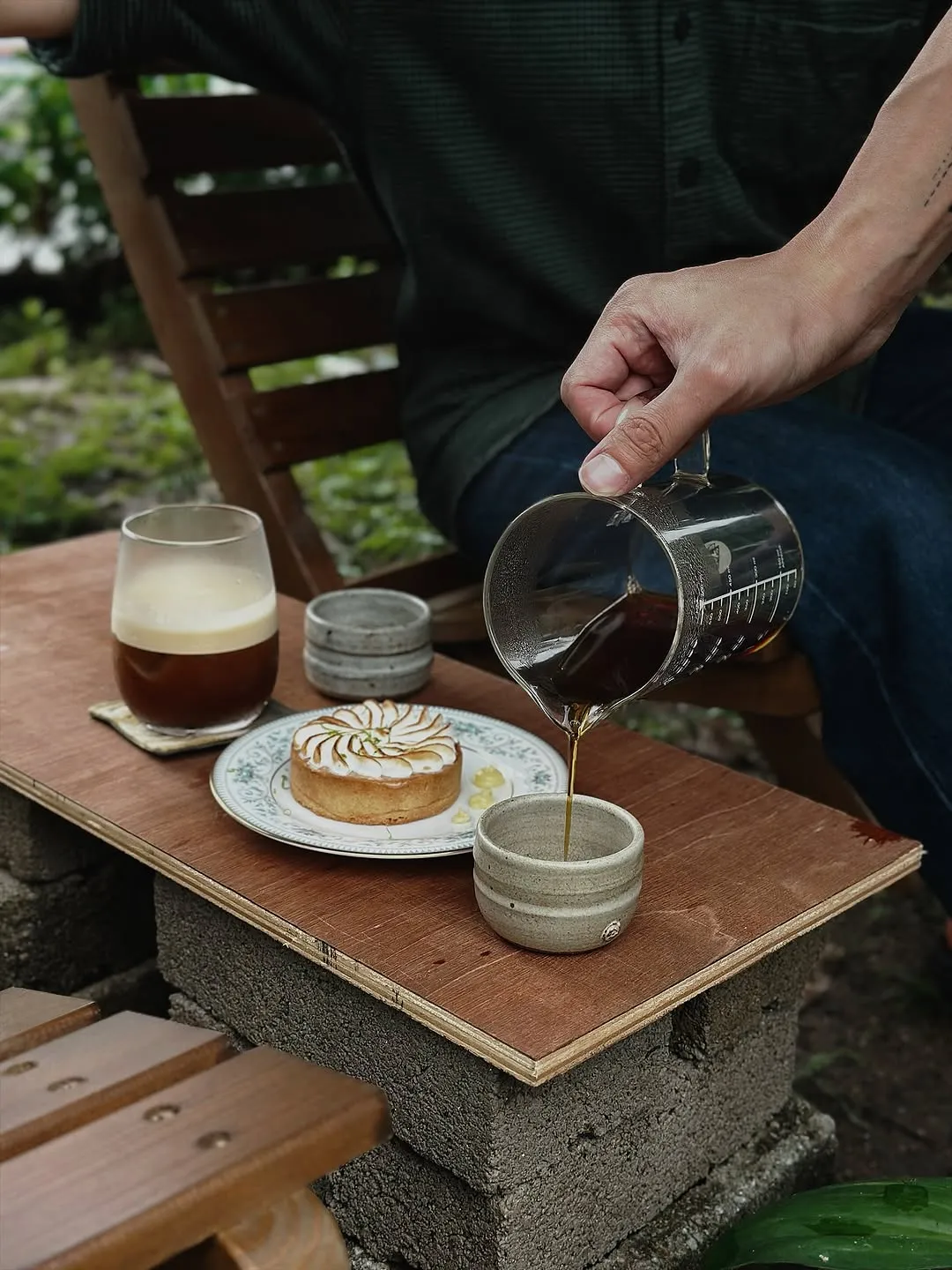 Pouring coffee into traditional cups beside a dessert on a wooden table.