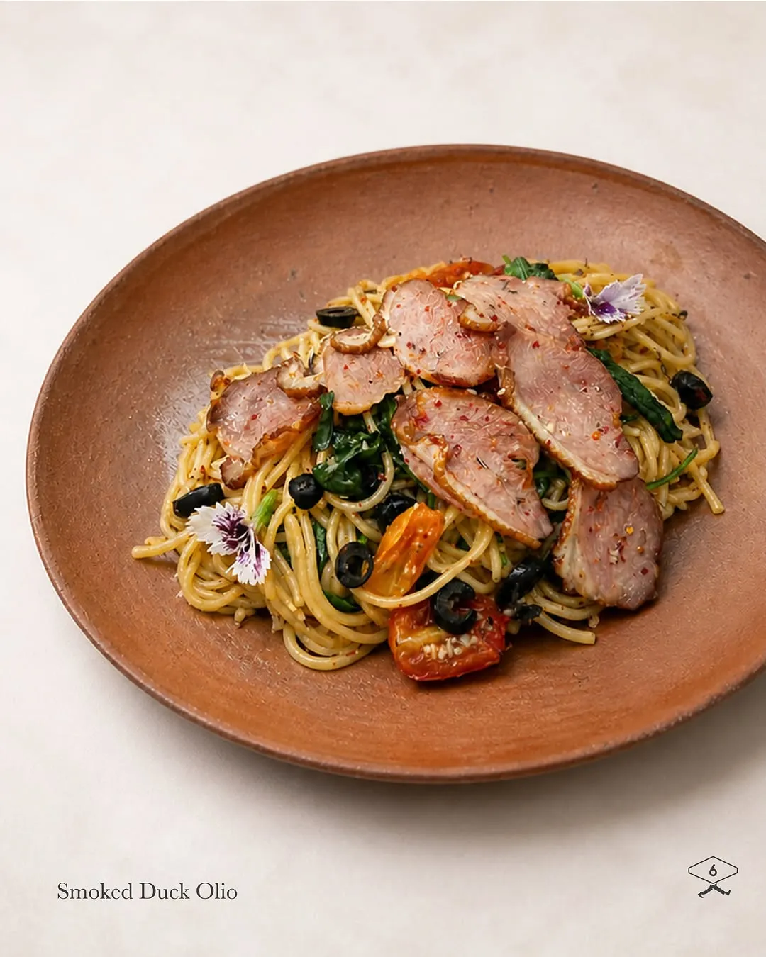 Alfredo pasta dish topped with smoked duck, parmesan, and basil leaves.