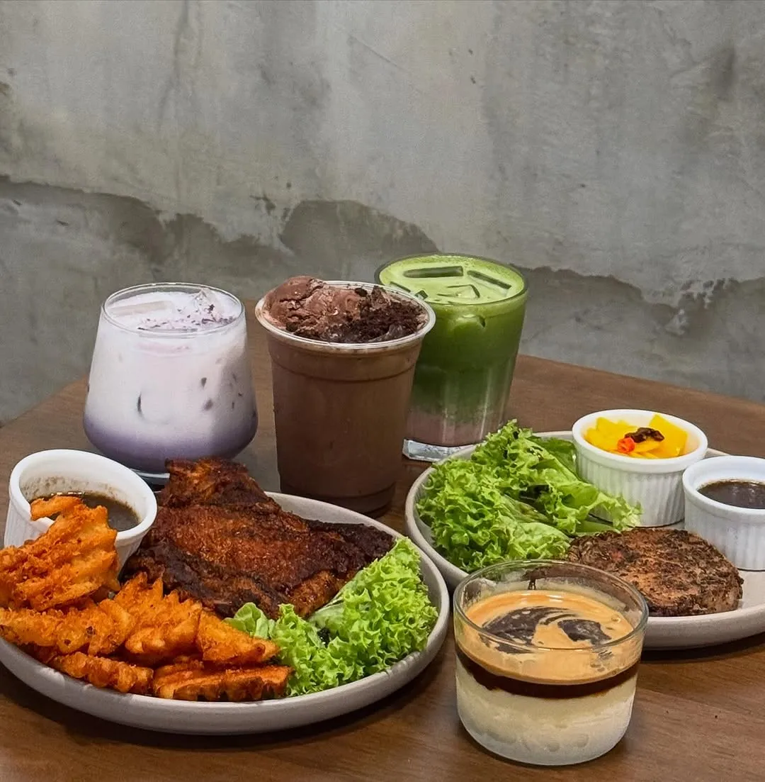 Halloween-themed feast with grilled chicken, drinks, and dessert on a table.