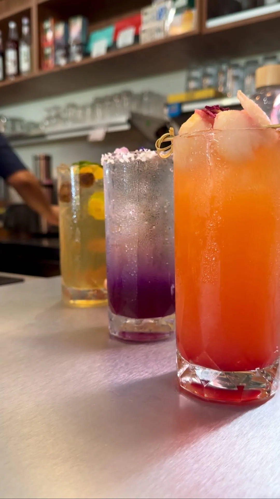 Close-up of four refreshing drinks in various colors on a bar counter.
