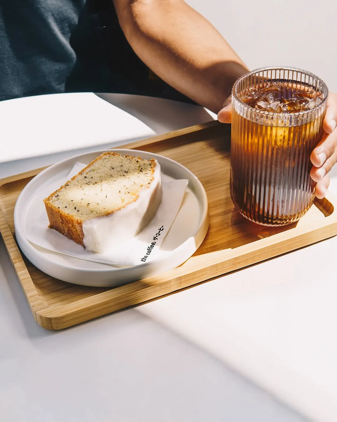 Lemon cake with a glossy glaze and an iced drink on a tray.