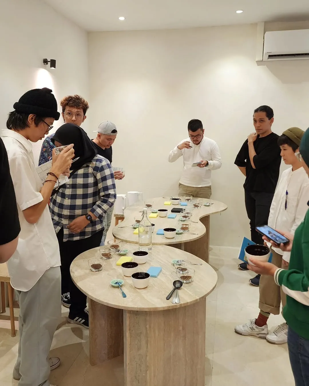 Group of people engaged in a coffee tasting event with various cups.