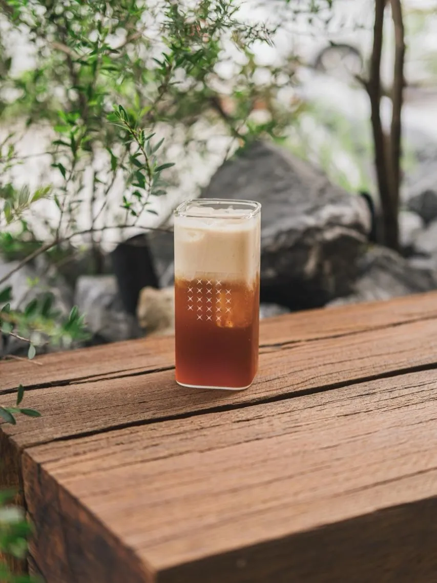 Refreshing iced beverage with foam resting on wooden surface.
