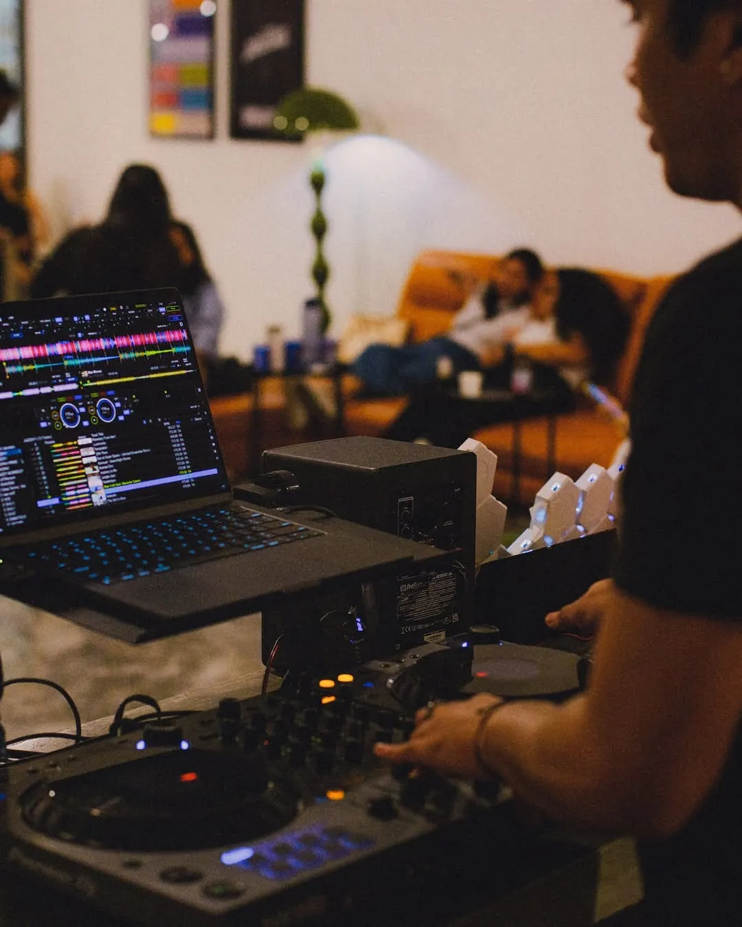 DJ mixing music at Pelisky during night hours with cozy seating in background.