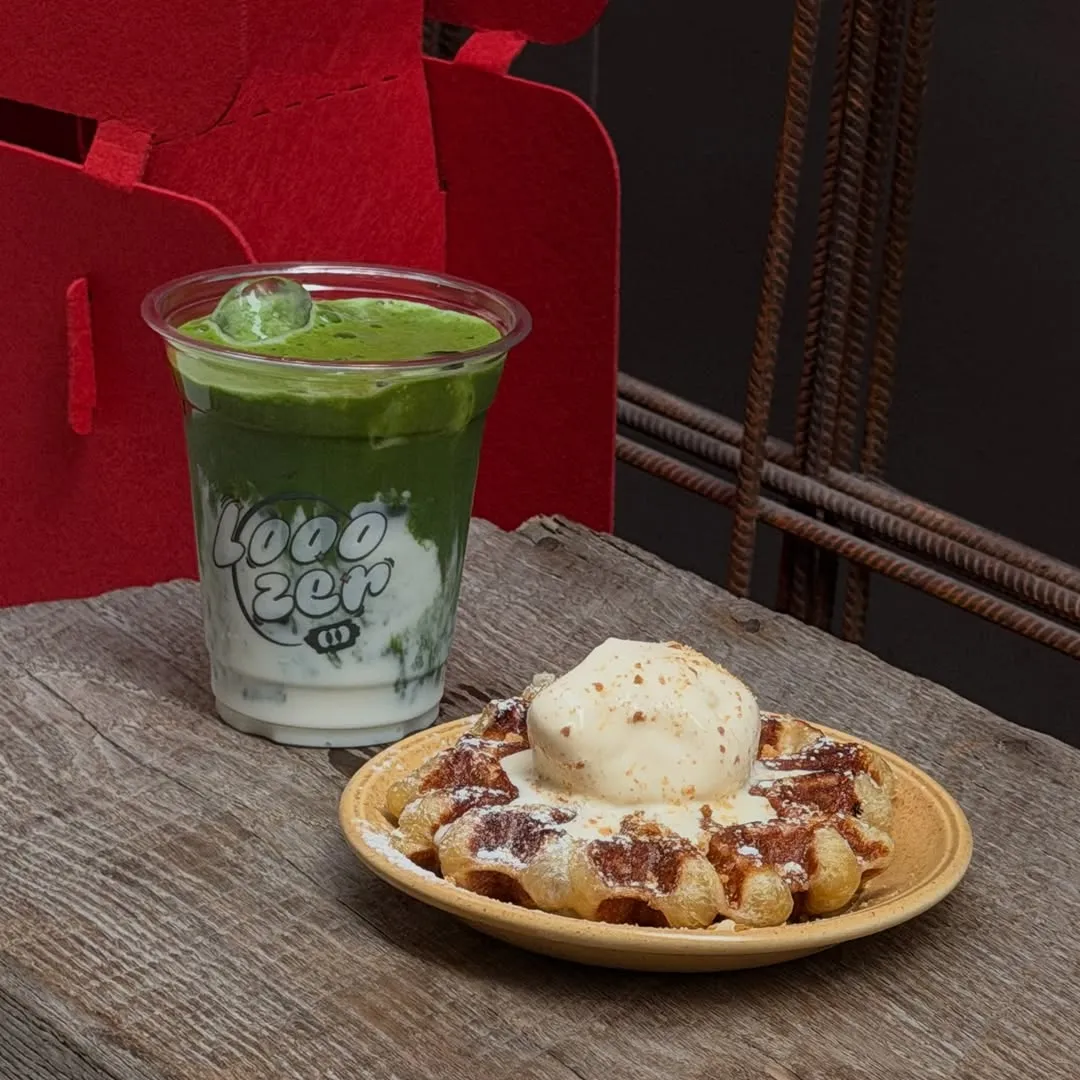 Matcha beverage and waffle dessert on a rustic wooden table.