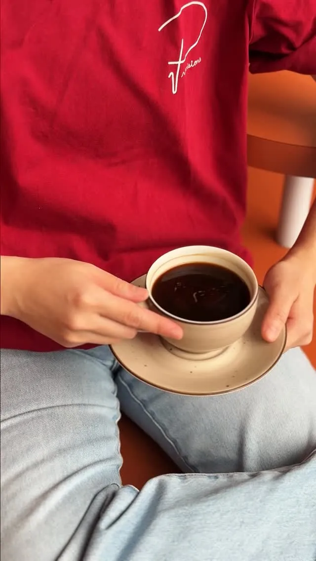 Hand holding a warm cup of coffee in a cozy cafe setting.